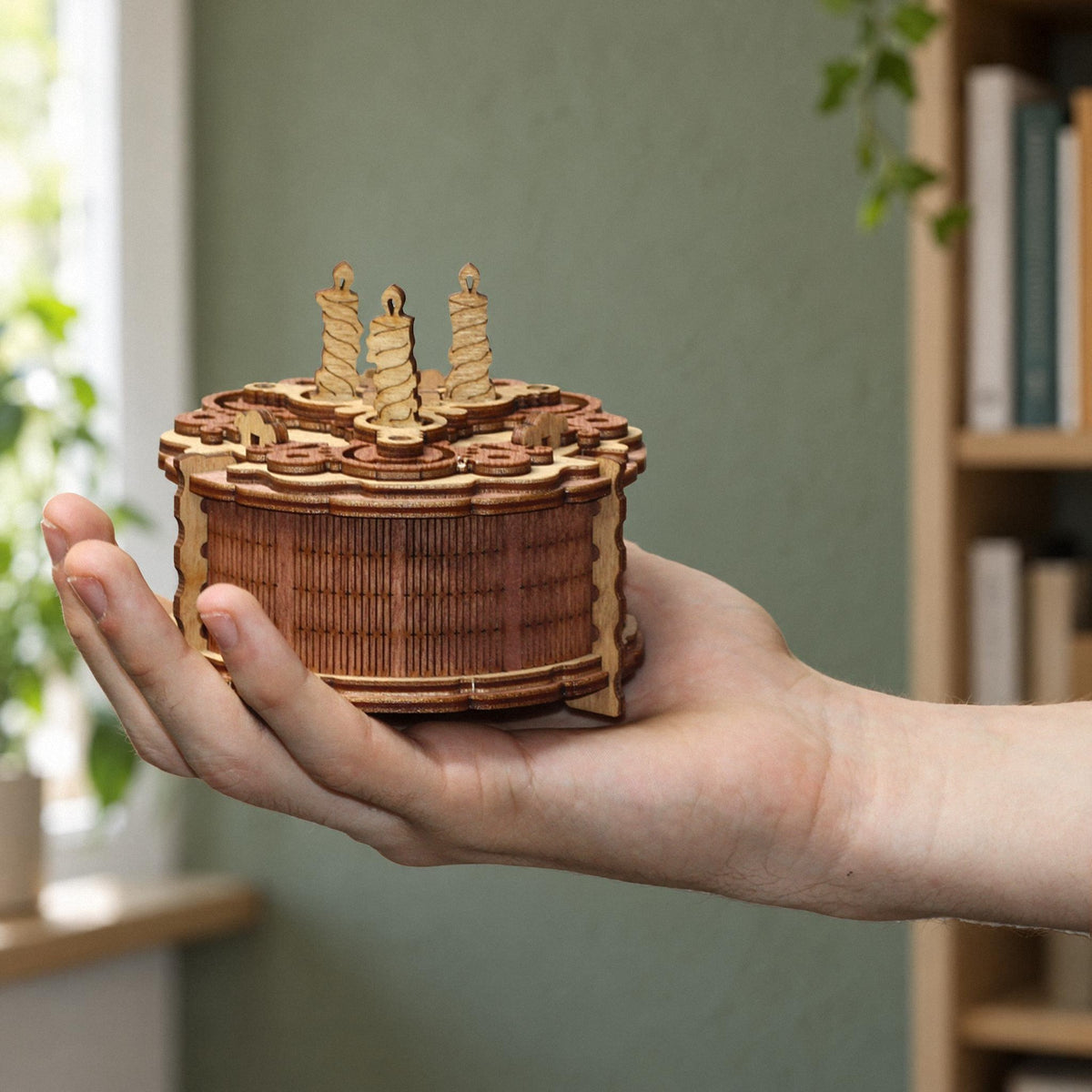 Coffret cadeau « Birthday Cake » : une boîte à énigmes où le gâteau en bois repose sur une main et montre bien sa taille dans le salon
