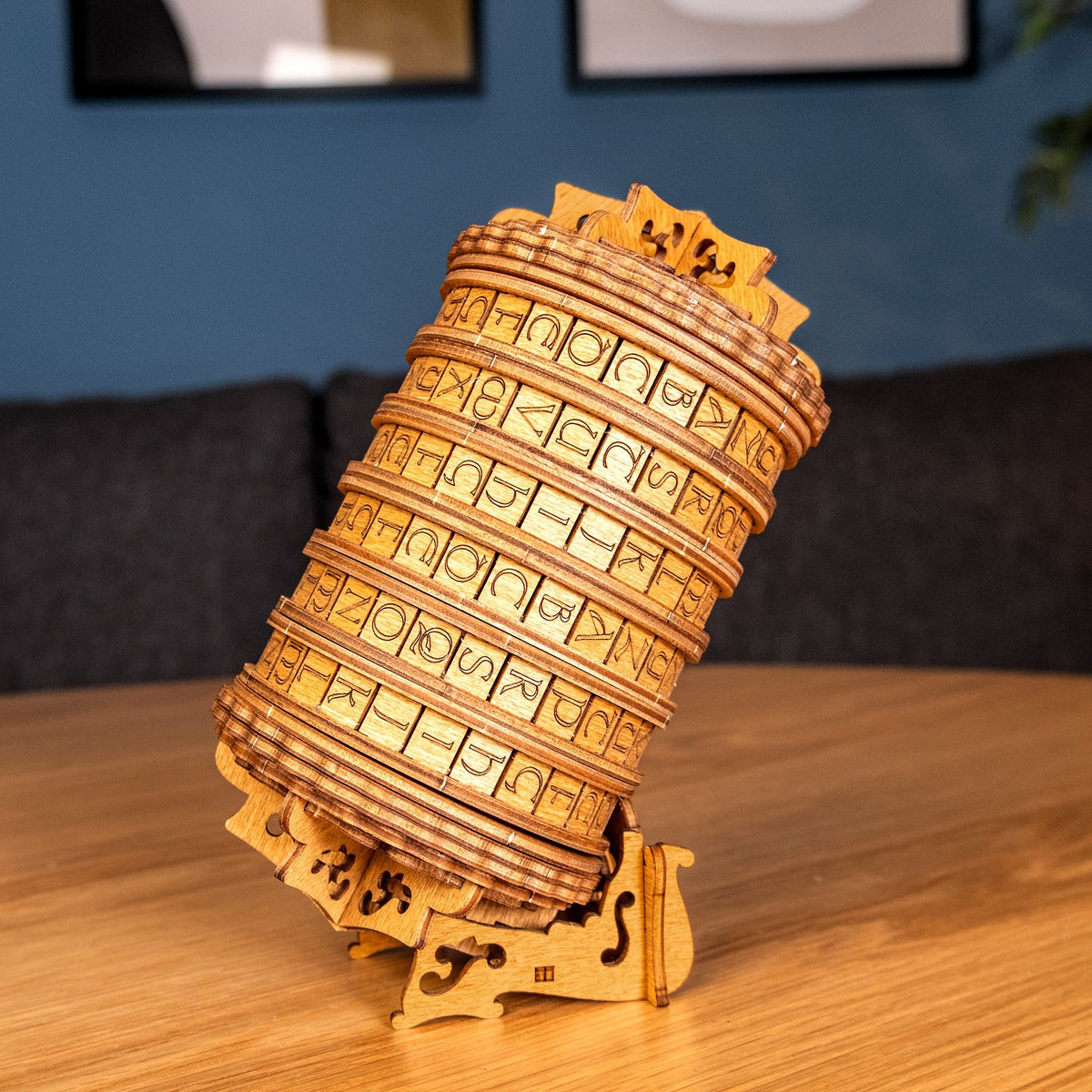 Cryptex Rätselbox auf einem runden Holztisch im Wohnzimmer vor dunkelblauer Wand und Sofa