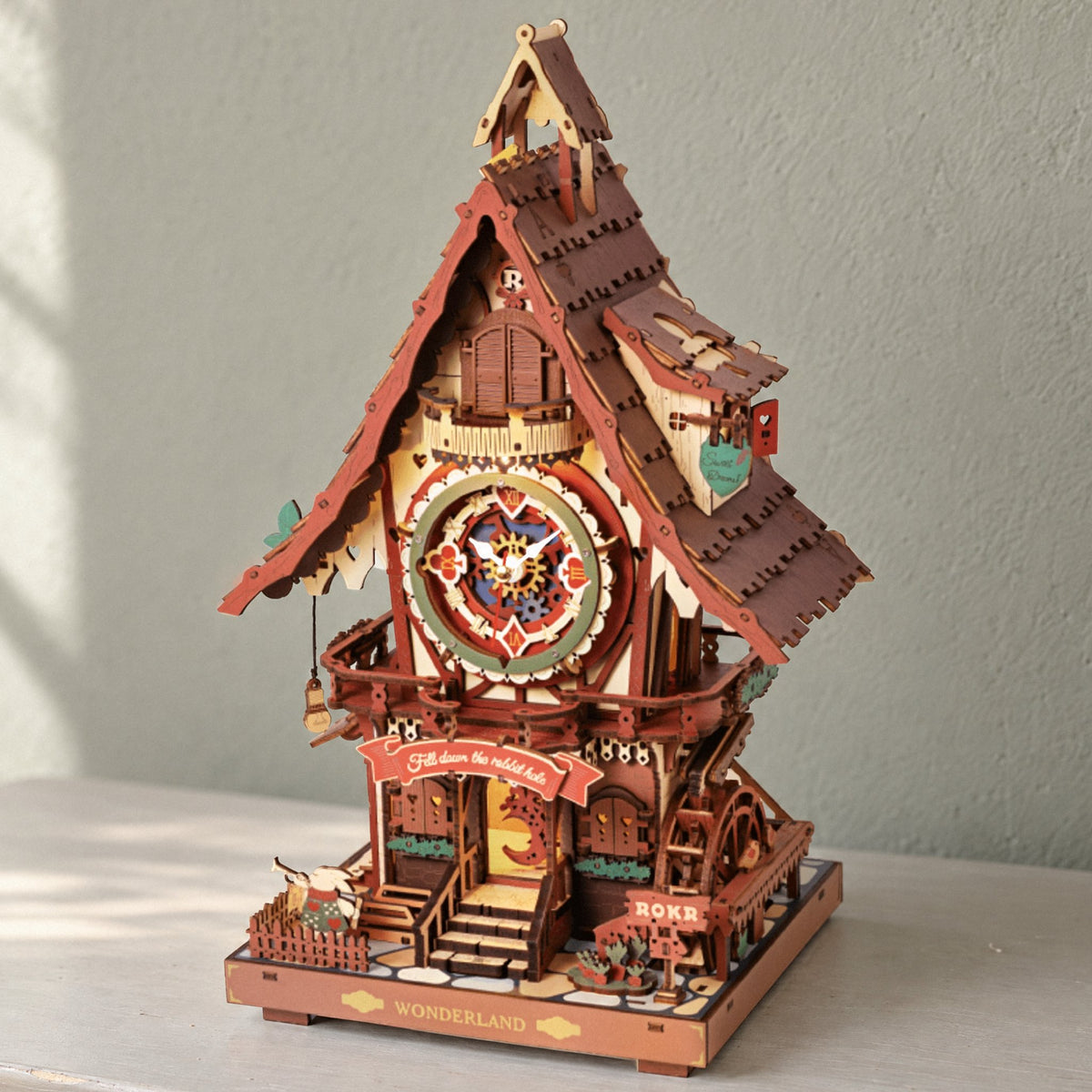 Cuckoo clock kit, fully assembled on a light gray dresser in front of a greenish-gray wall in natural light