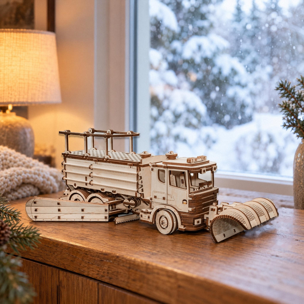 Schneeräumer-LKW aus Holz auf dem Sideboard vor dem Fenster mit verschneitem Garten, mechanischer Bausatz