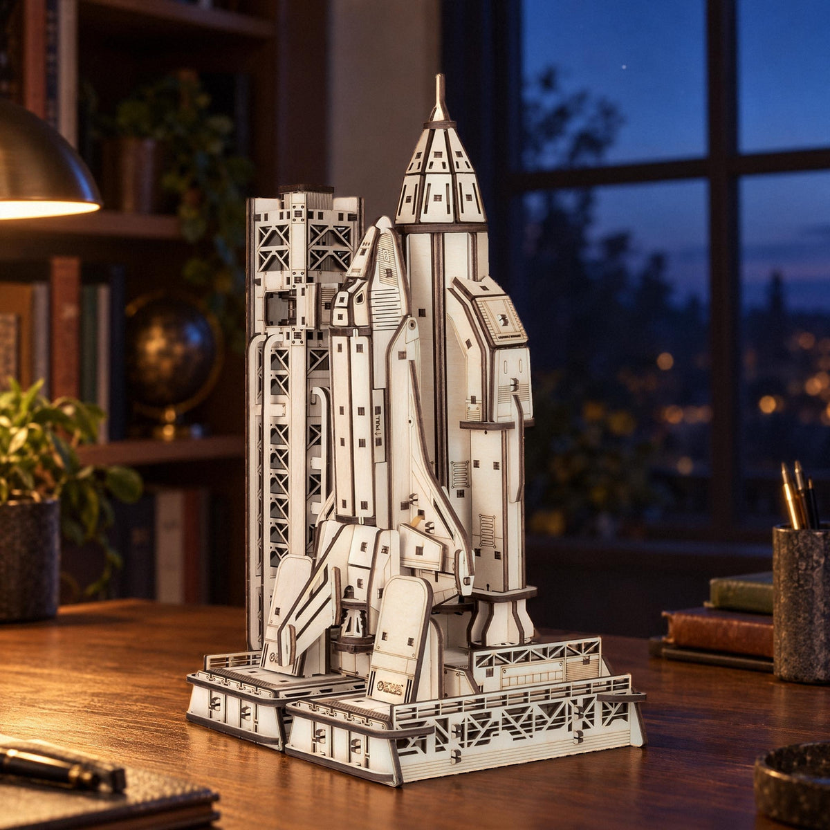 A wooden space shuttle with a launch tower on the desk in the study, bathed in the warm light of the lamp in the evening
