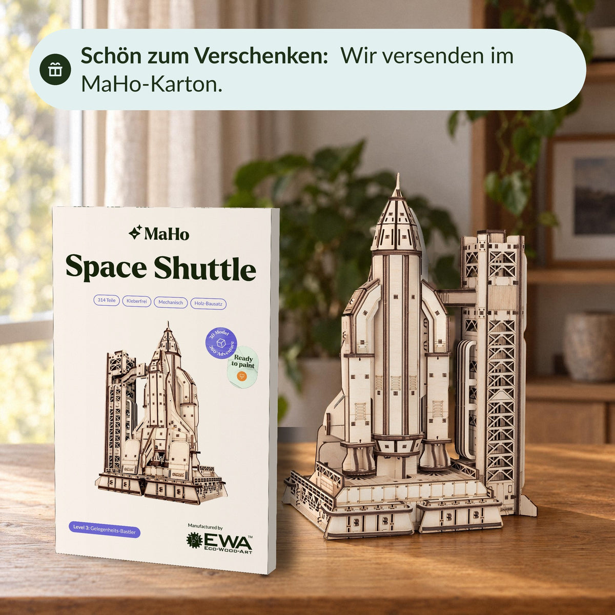 A wooden model of the Space Shuttle next to the upright MaHo box with a banderole on the wooden table—a lovely gift