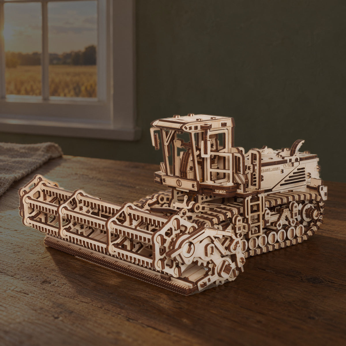 Mower CS-150C – Schwadmäher, fertiges Holzmodell auf dem Eichentisch einer Landhausküche, Fenster mit Blick aufs Kornfeld