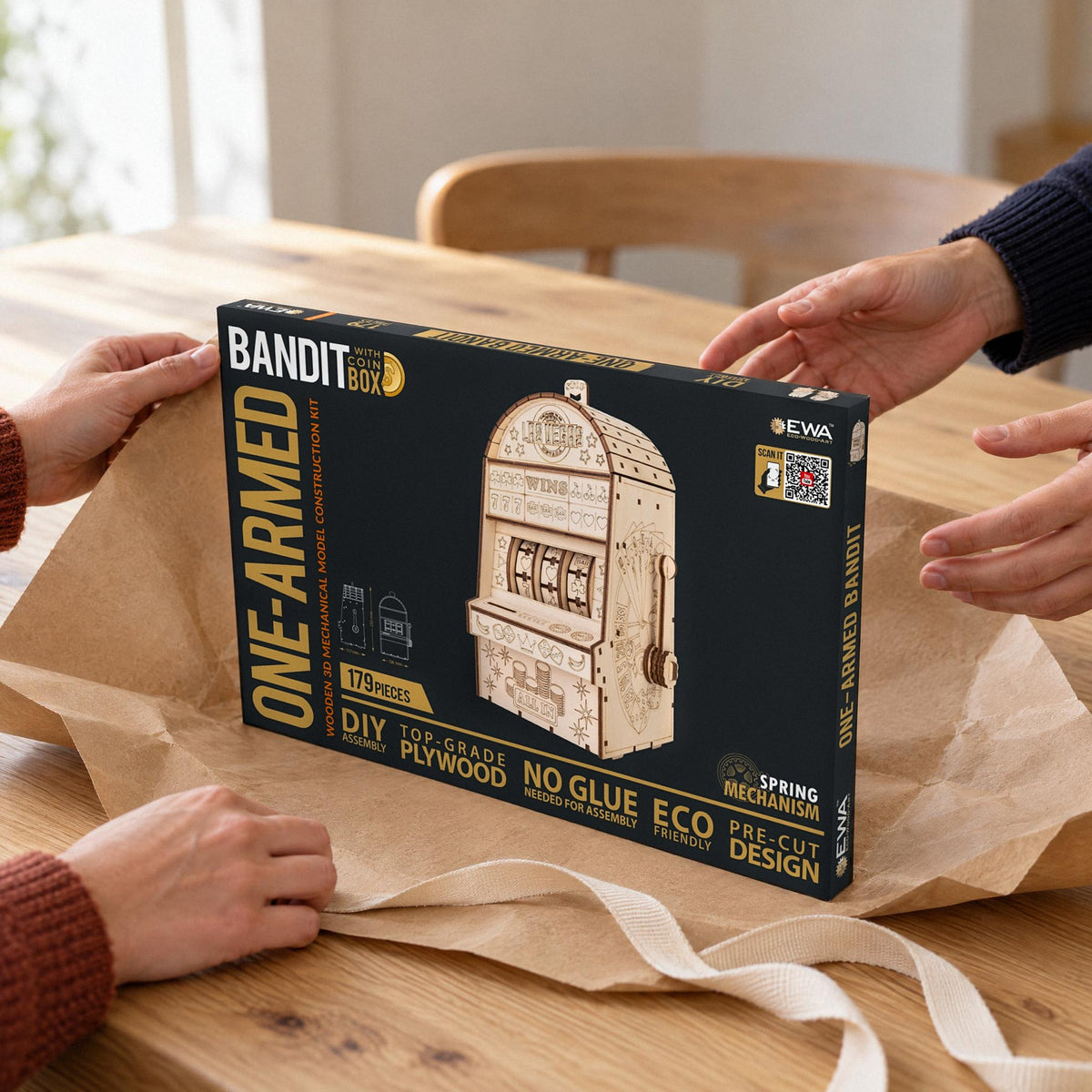 Einarmiger Bandit Holzbausatz als Geschenk, der Bausatz-Karton auf Packpapier am Esstisch überreicht
