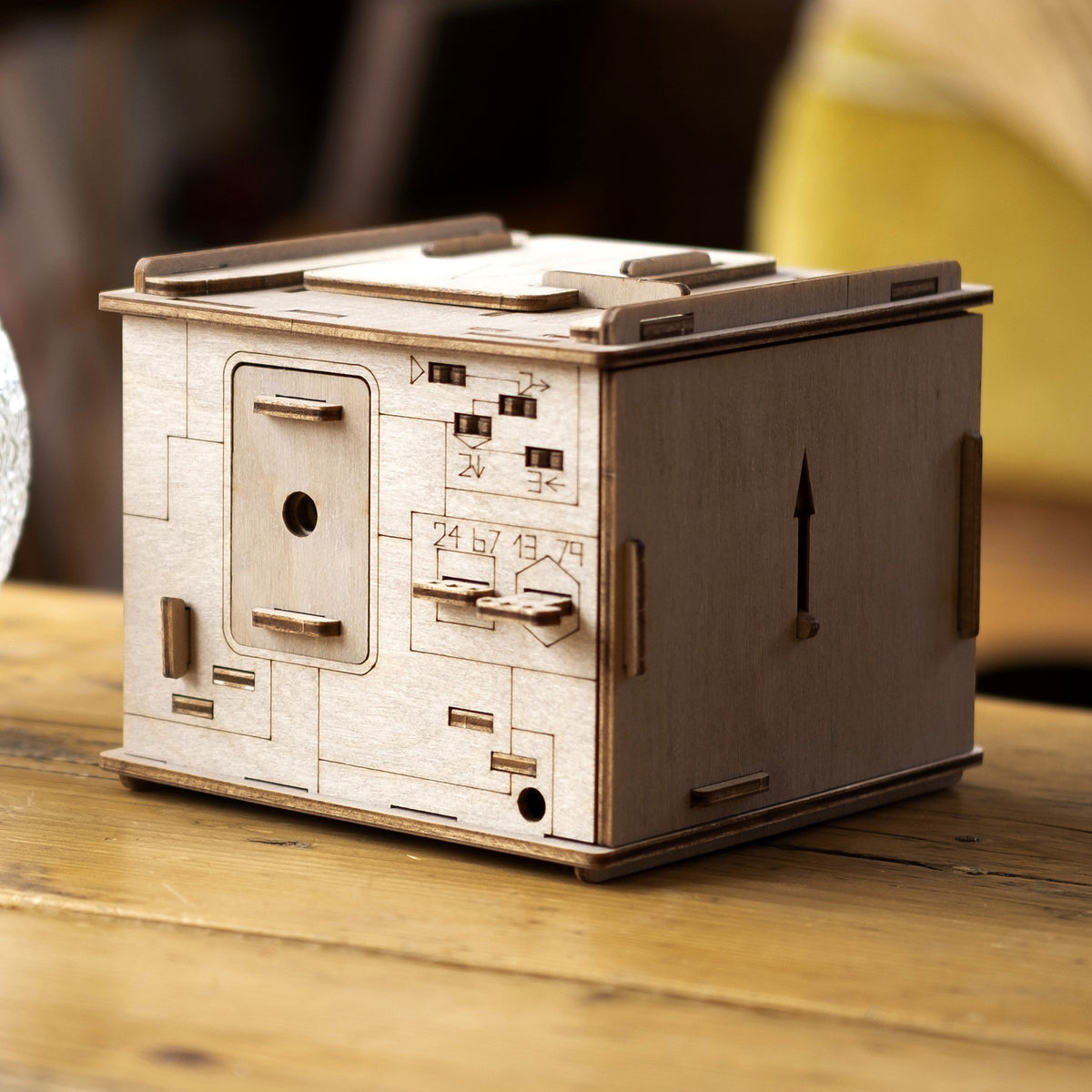 Space Box Riddle Box made of birch wood, closed, on an old wooden table next to a glass vase in natural light