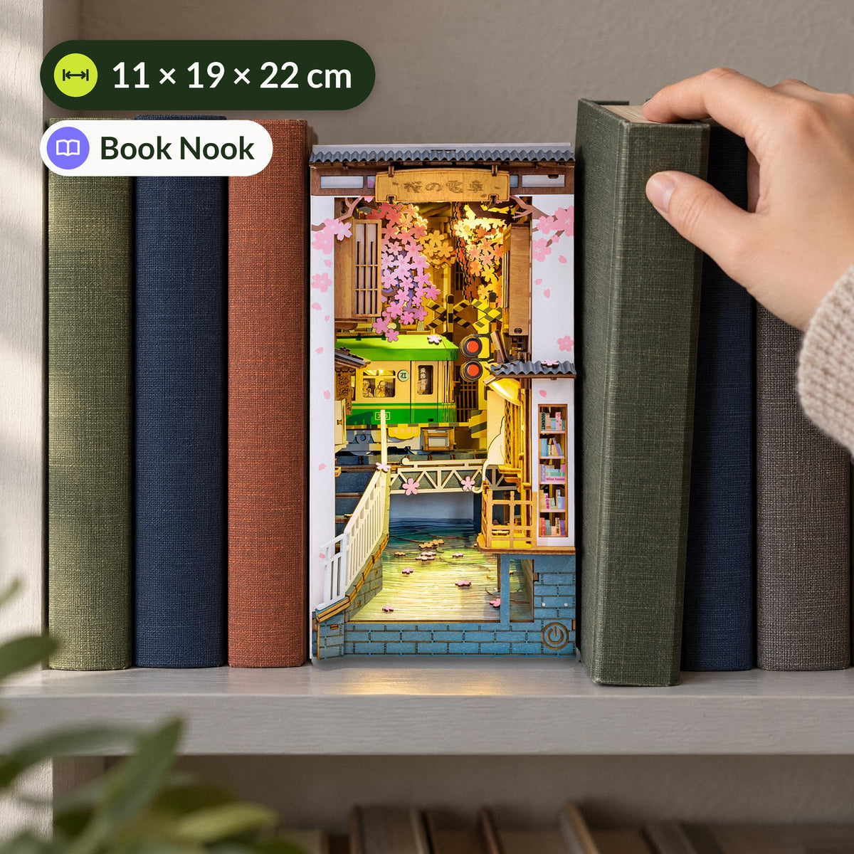 Sakura Densya Book Nook, among books on a shelf, a hand pulling a book out, 11 × 19 × 22 cm in size