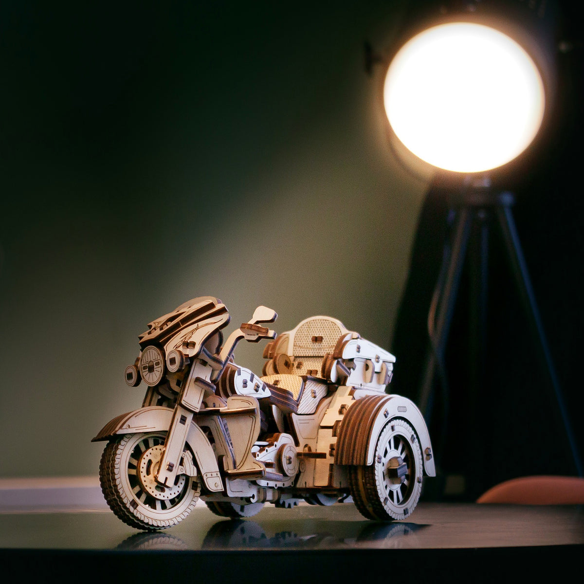 Holz-Trike im warmen Licht eines Scheinwerfers auf einem dunklen Regal als Deko-Objekt