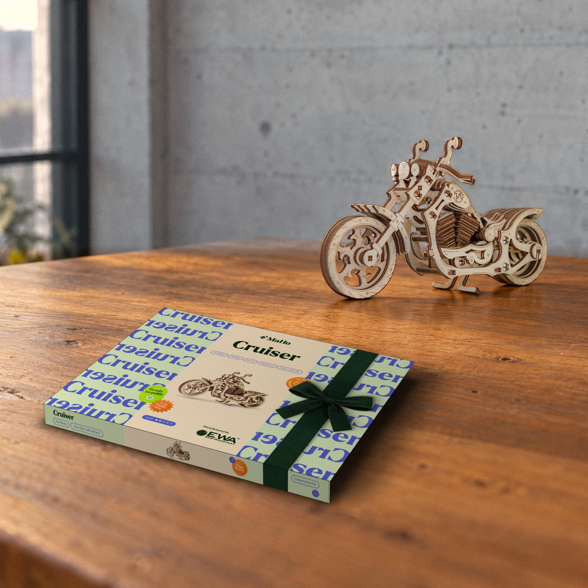 Een cruiserfiets als cadeau: een MaHo-doos met een donkergroene strik op de eettafel, met daarachter de afgewerkte houten motorfiets