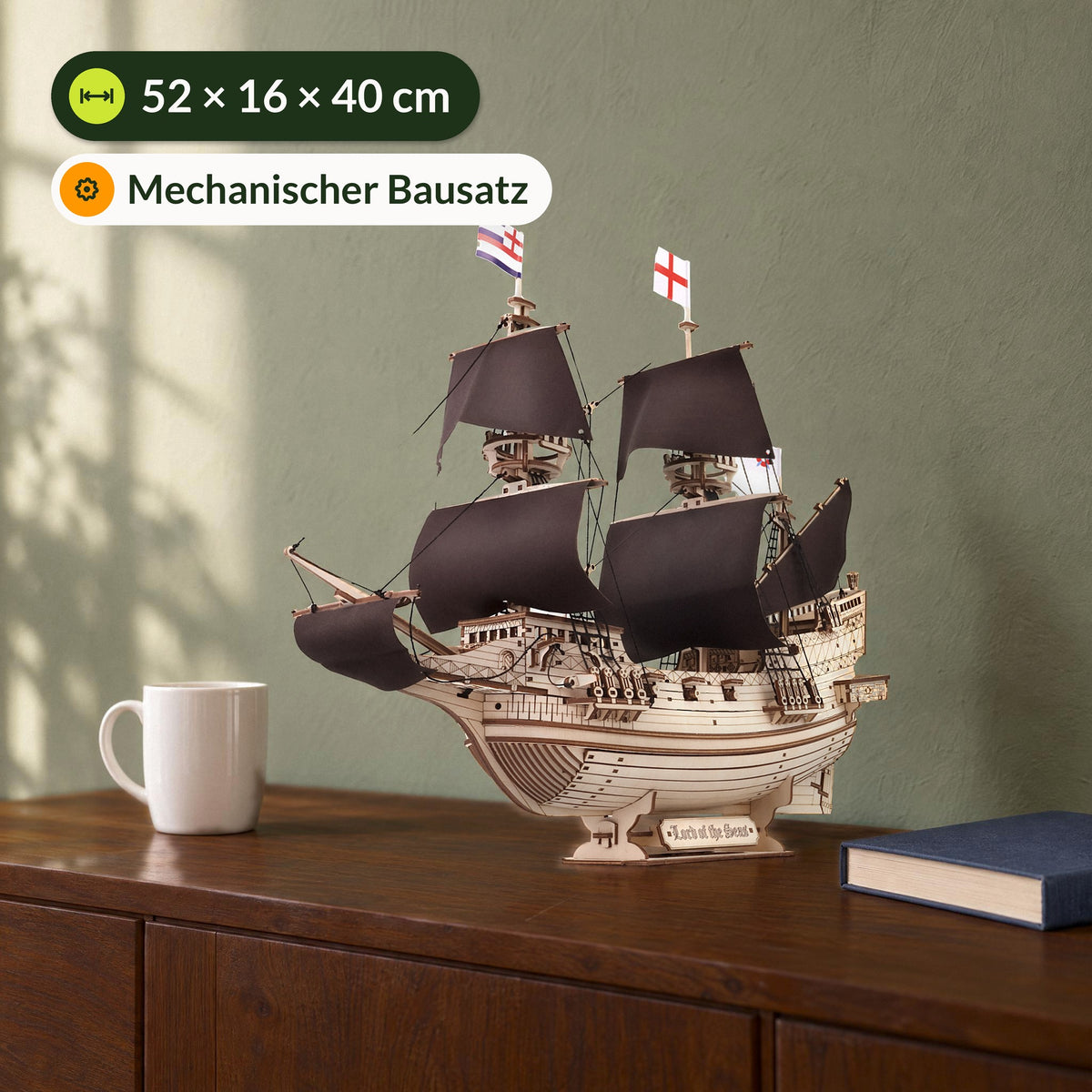 "Lord of the Seas" wooden model kit, measuring 52 × 16 × 40 cm, on a sideboard next to a white cup and a book