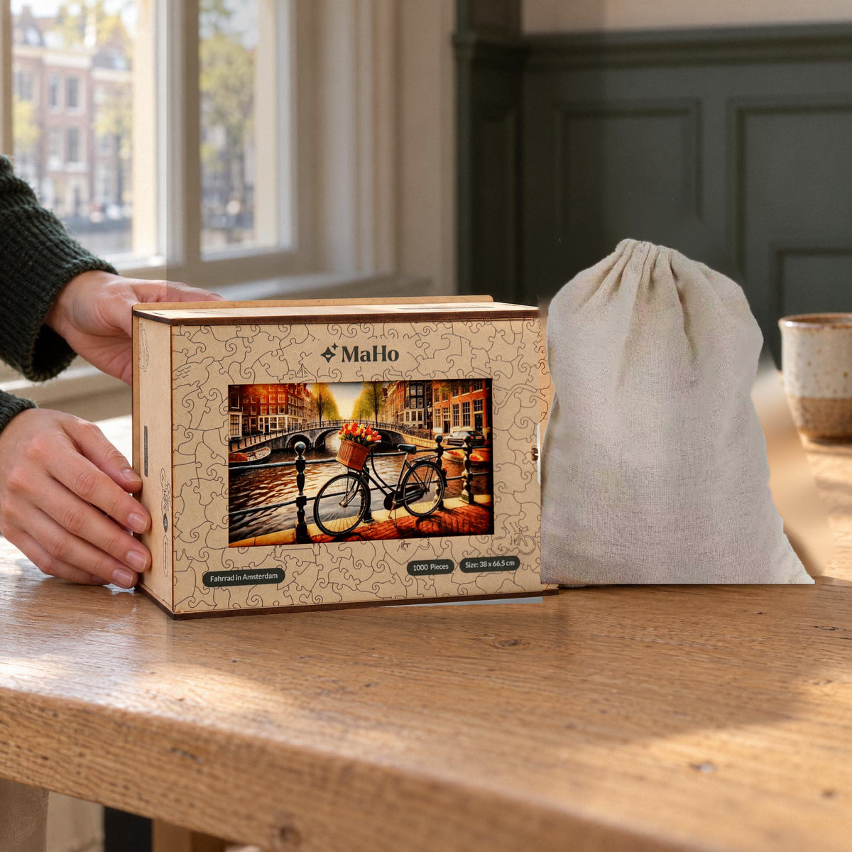 Puzzle en bois « Vélo à Amsterdam », coffret en bois haut de gamme avec un motif de canaux et un sac en tissu offert en cadeau, posé sur une table en chêne