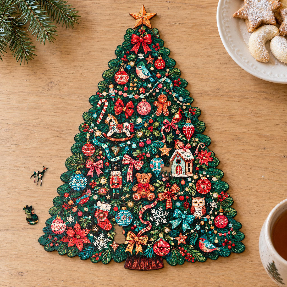 Festlicher Weihnachtsbaum Holzpuzzle, Baumform auf hellem Eichentisch, daneben Plätzchen und zwei Figurenteile
