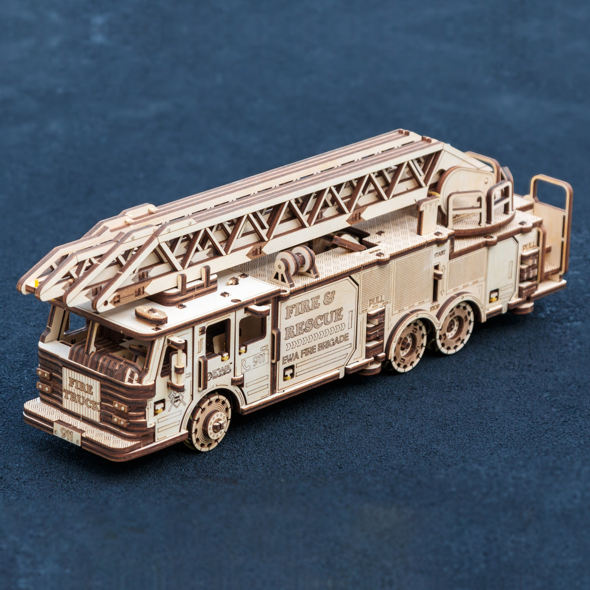 Camion de pompiers mécanique « Maquette en bois », modèle déjà assemblé avec une échelle pivotante, vu de profil sur fond bleu foncé
