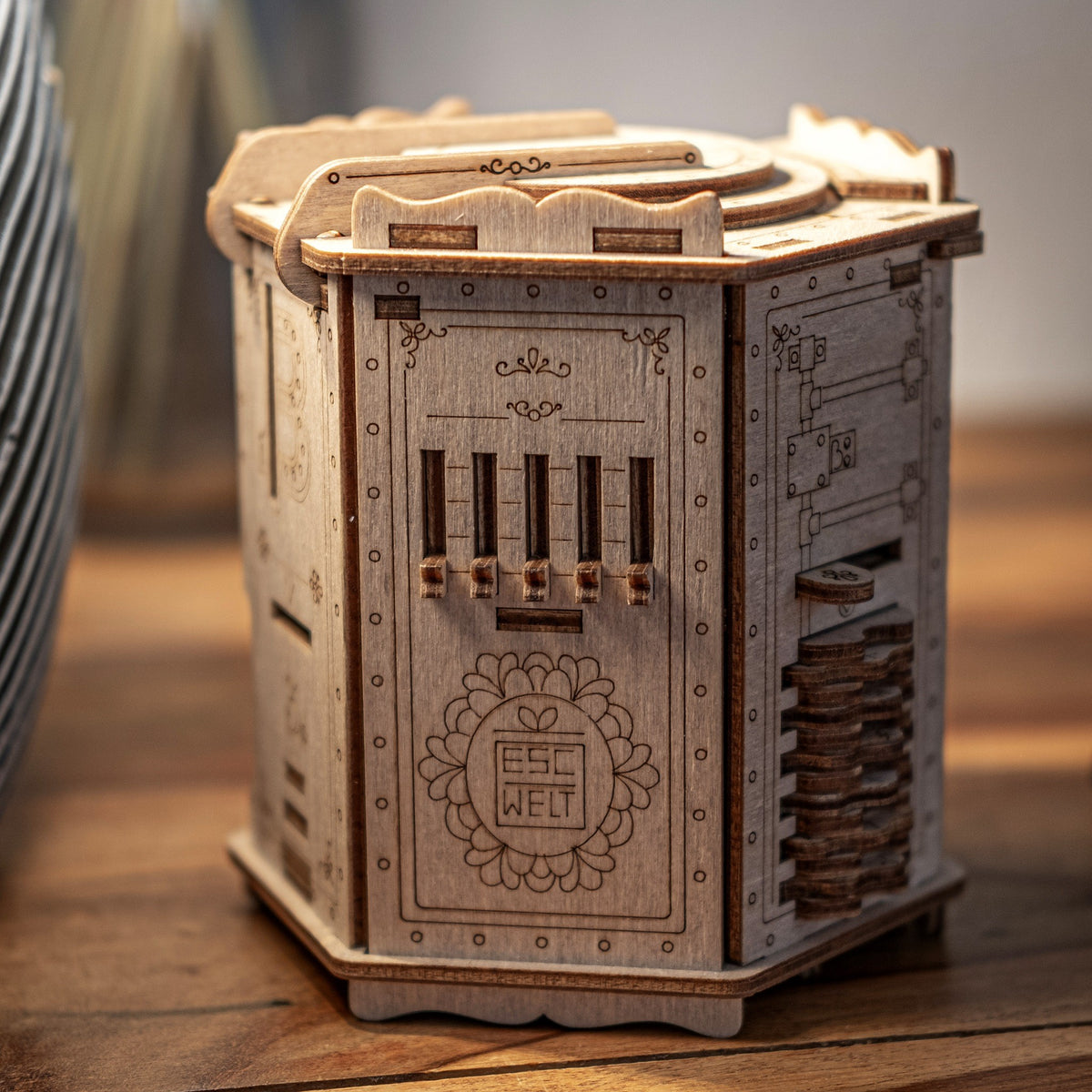 Boîte à énigmes Fort Knox Pro en bois de bouleau, posée fermée sur une table en bois foncé, baignée d'une lumière chaude venant du côté