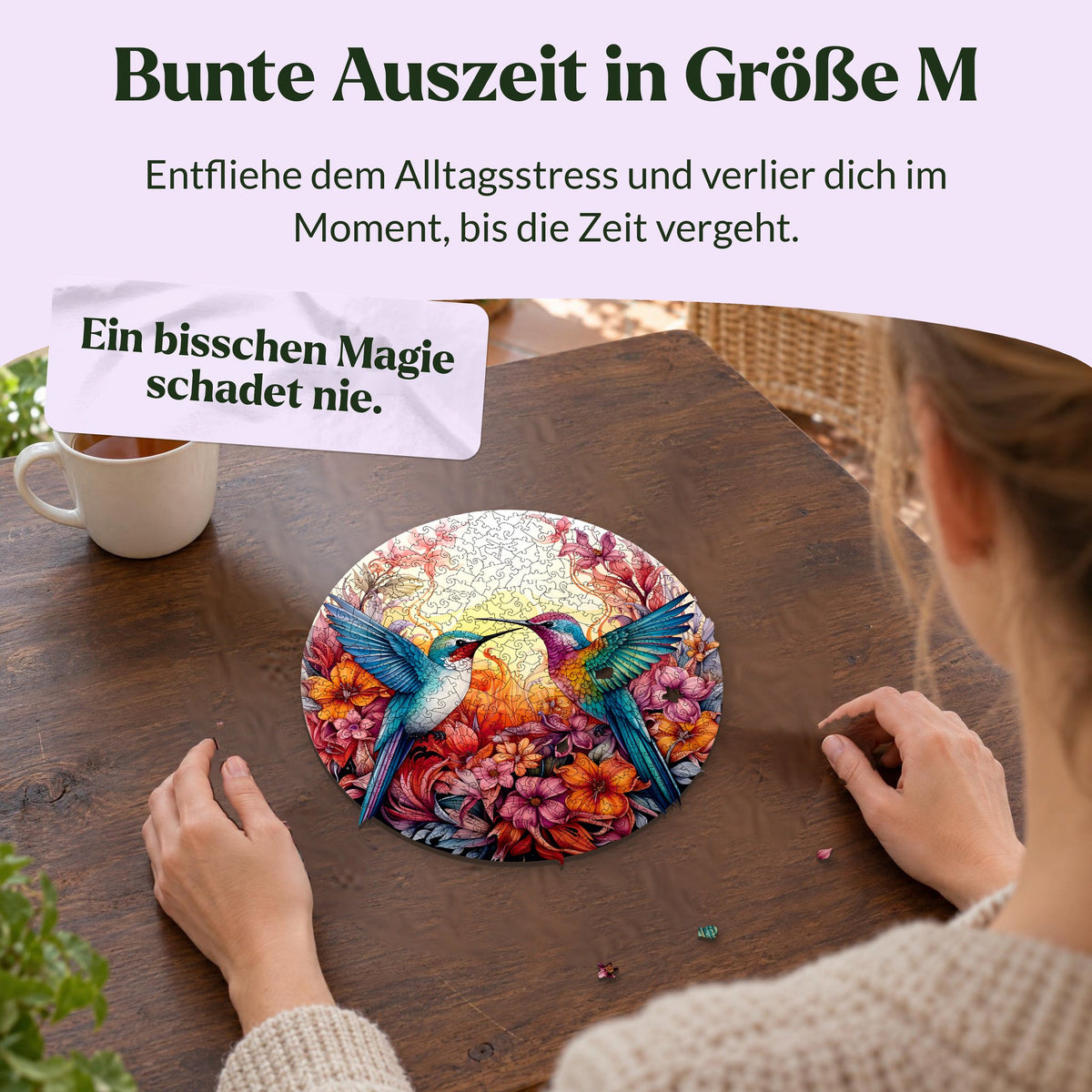 "Happy Hummingbirds" Mandala Wooden Puzzle, a woman putting together the puzzle at a wooden table in a bright sunroom, Size M, loose puzzle pieces next to her