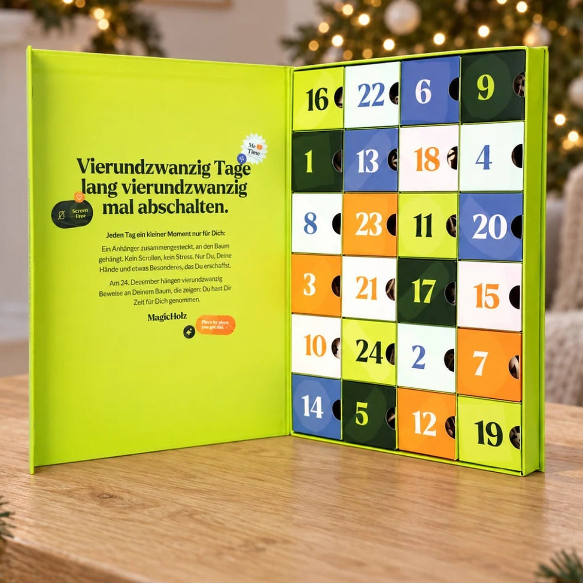 "Magical Moments" Advent calendar, opened with 24 colorful doors, on the wooden table in front of the Christmas tree