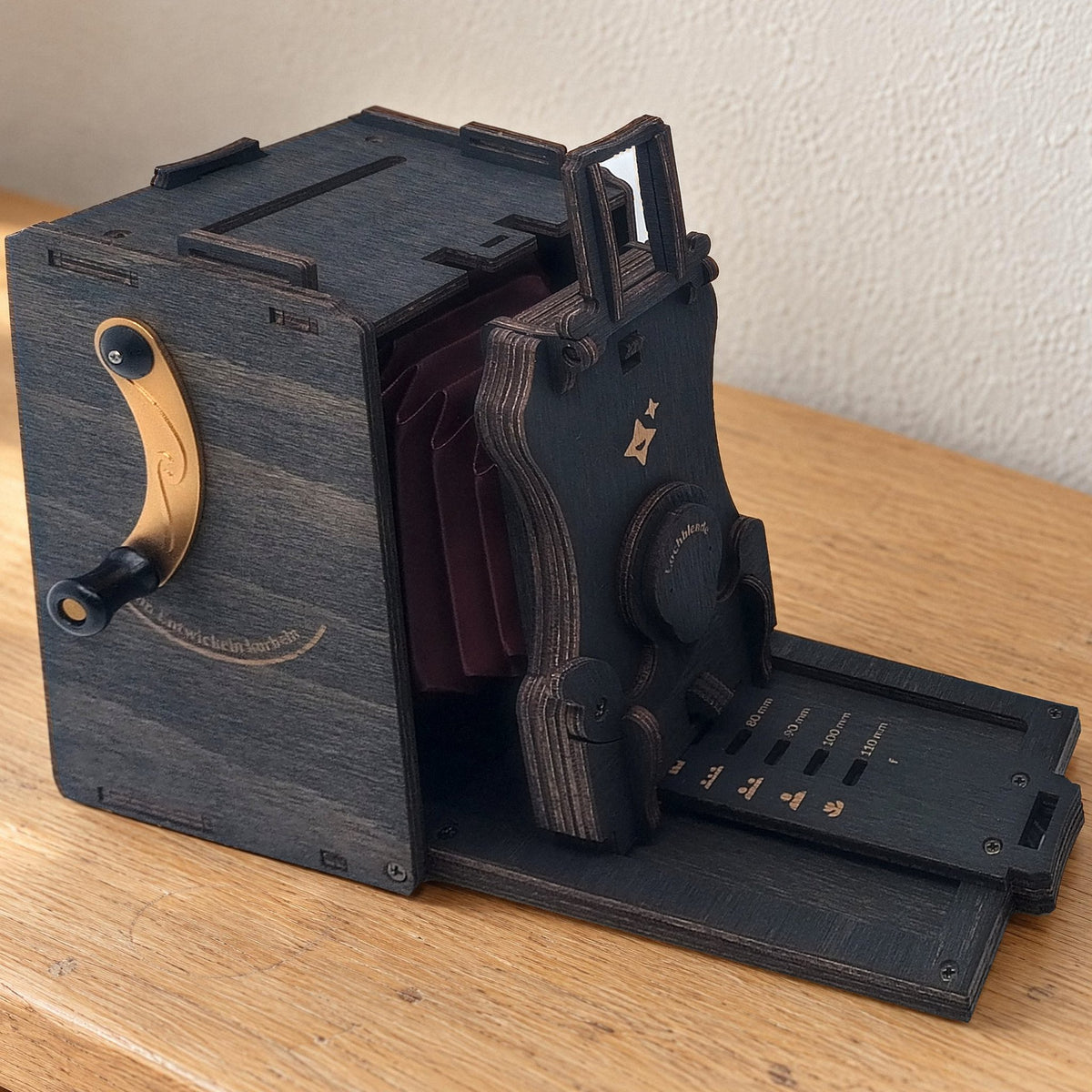 Instant camera kit, MaHo version with star engraving and gold crank, displayed on a light oak sideboard in the morning light