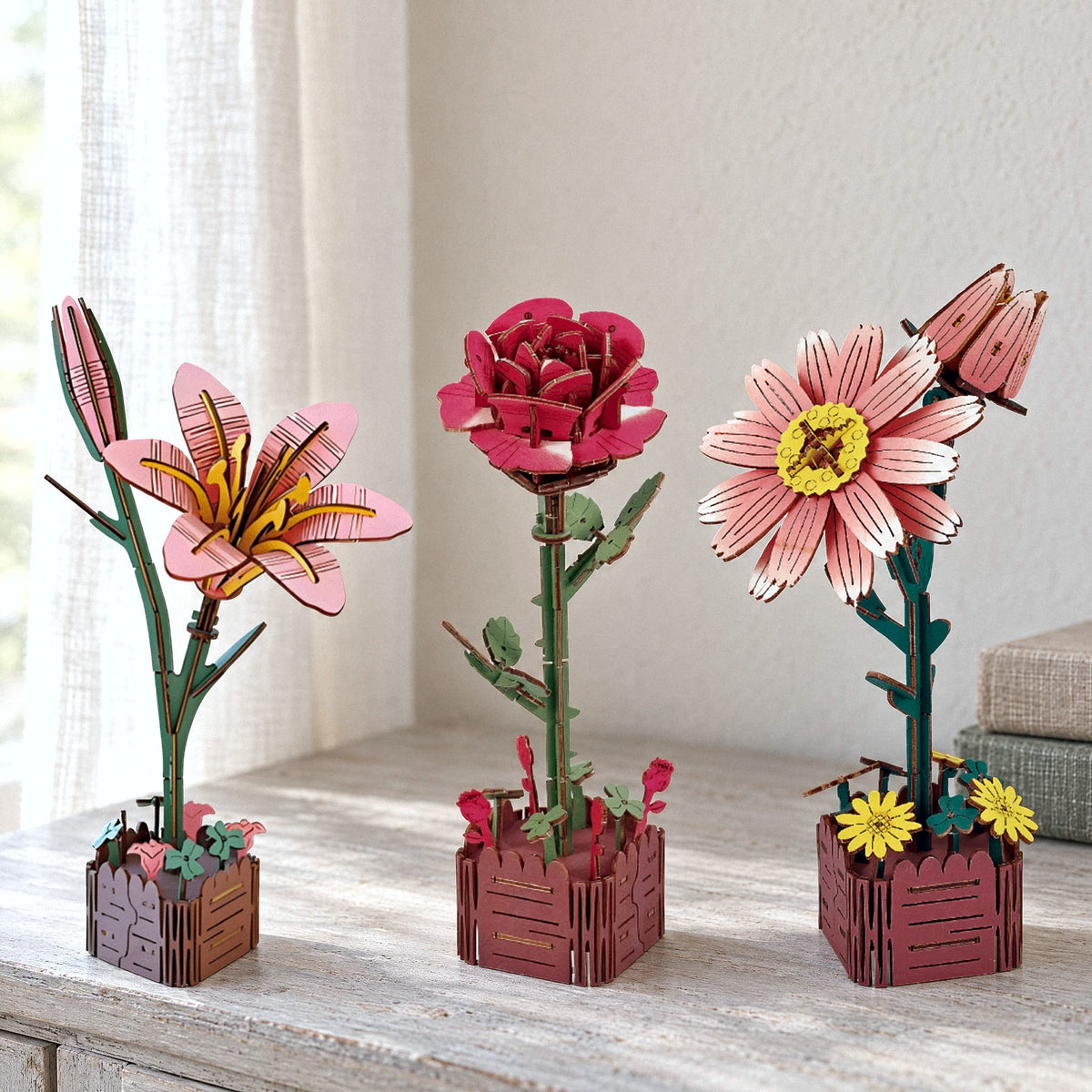 Trio de fleurs « Printemps éternel », coffret « Romantique » : lys, rose et pâquerette en bois sur un buffet clair