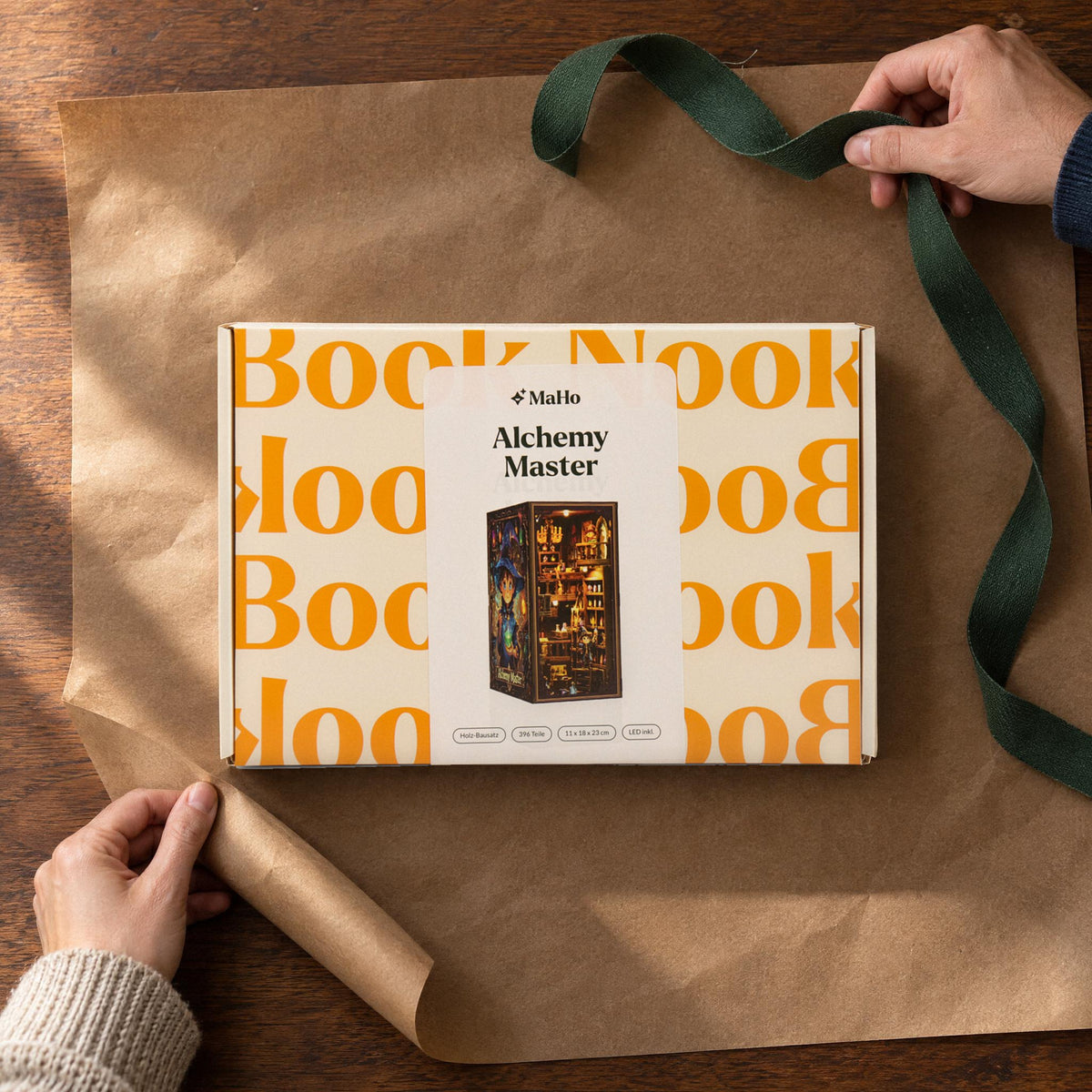 Alchemy Master Book Nook, as a gift: the " MagicHolz" box wrapped in packing paper with a green ribbon, two hands
