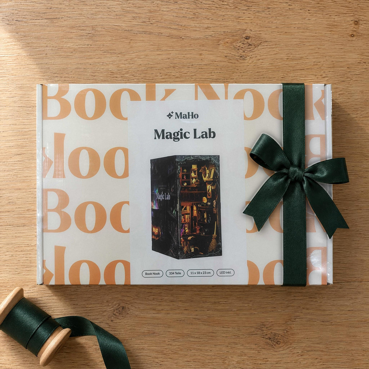 Magic Lab Book Nook, gesloten MaHo-doos met een donkergroene satijnen strik op een lichte eikenhouten tafel