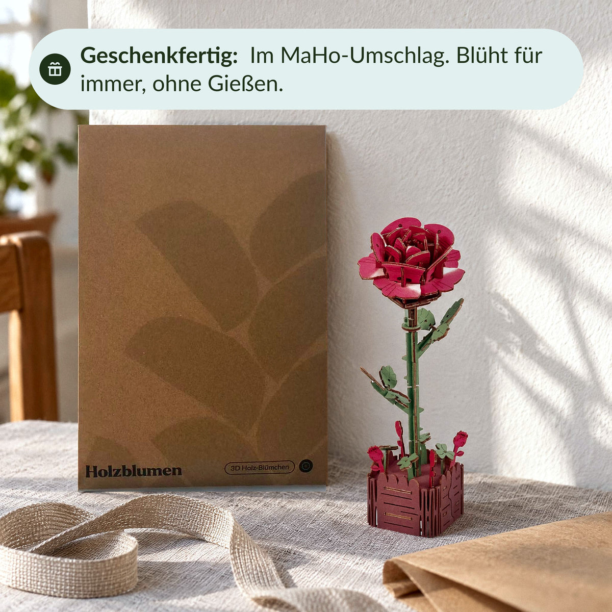 Holzblumen als Geschenk: Rose neben dem MaHo-Umschlag Holzblumen, Leinenband auf dem Tisch