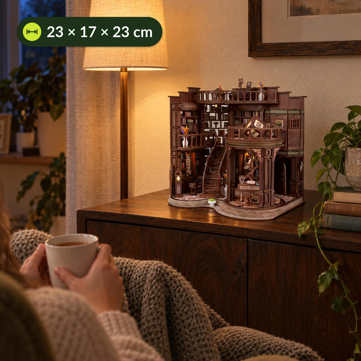 Grand Library Miniaturhaus leuchtet im Wohnzimmer auf dem Sideboard, vorne eine Frau mit Tee, Maße 23 × 17 × 23 cm