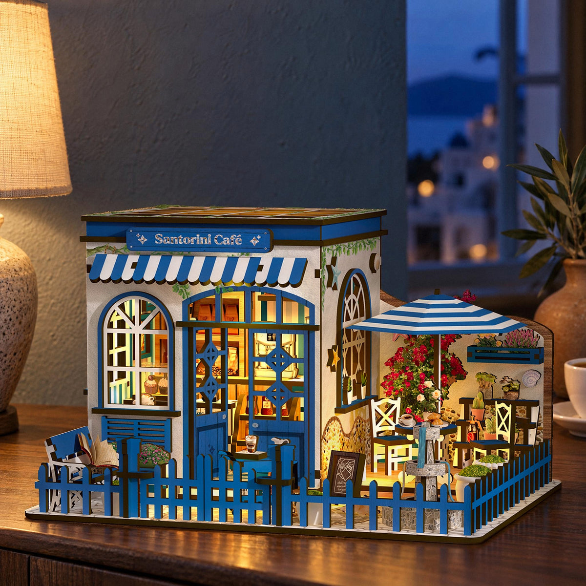 Santorini Café Miniaturhaus, leuchtet abends auf dem Sideboard, warmes Licht aus Fenstern und Terrasse, Lampe am Rand