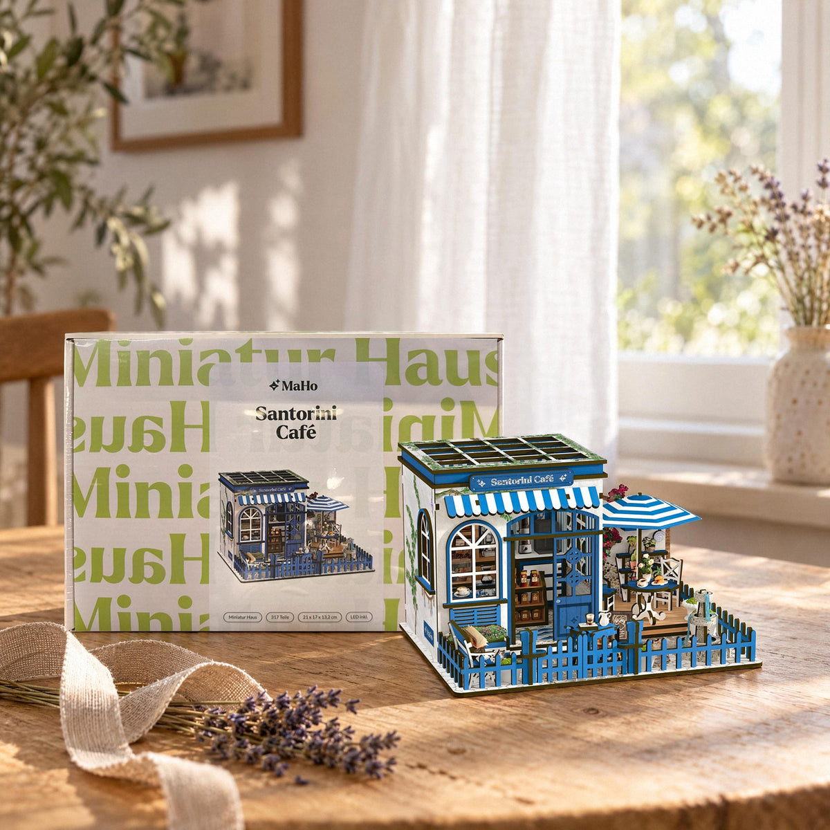 Santorini Café Miniaturhaus, als Geschenk neben dem MaHo-Karton auf dem Tisch, mit Leinenband und Lavendel
