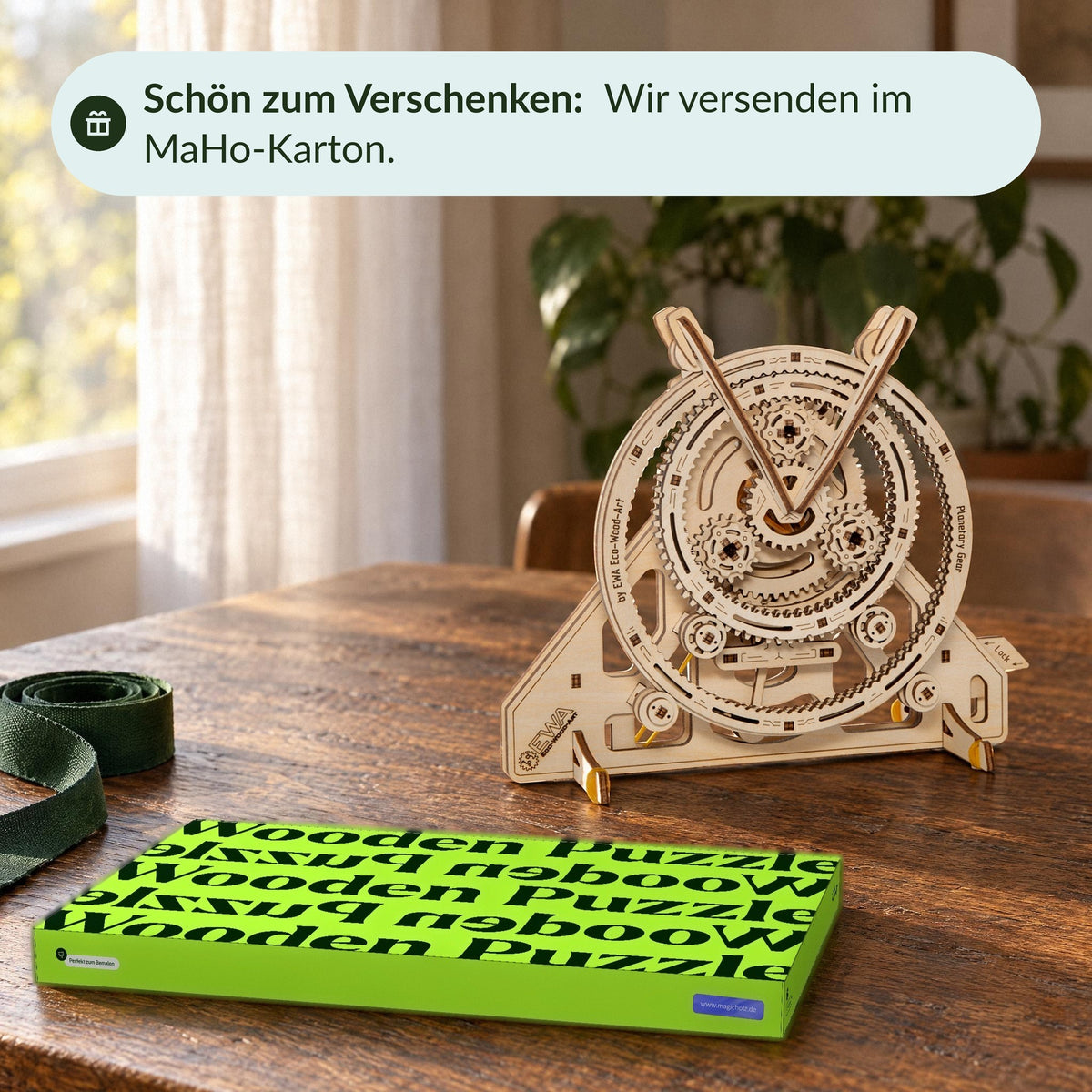 Planetary gear set behind the sealed MaHo box on the dining table, with a green ribbon next to it—perfect for a gift