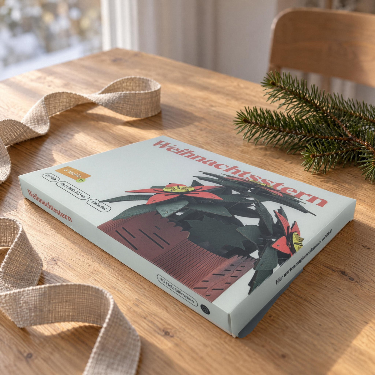 Houten kerstster als cadeau: witte doos van de grote bouwset met linnen lint en een dennen takje op eikenhout