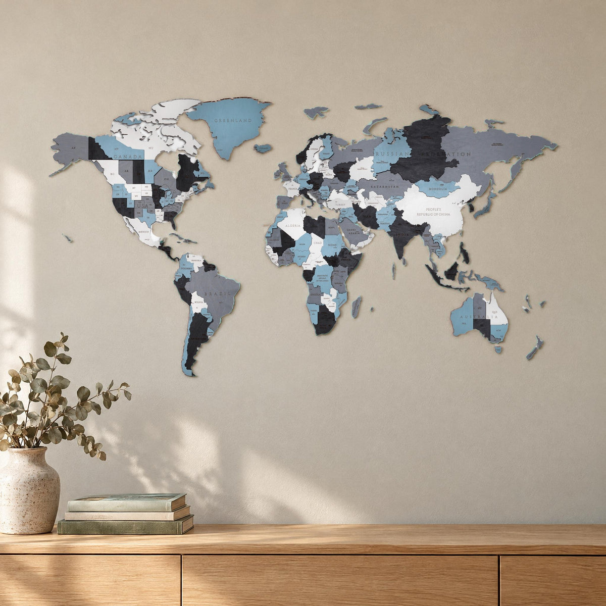 Carte du monde en bois « Rauchige Träume » accrochée au mur au-dessus d'un buffet clair dans le salon