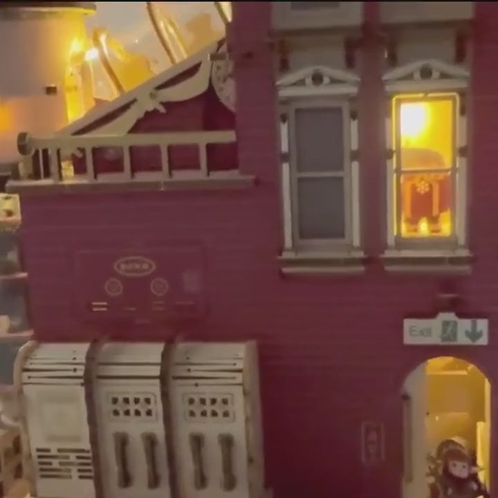 The wooden Dream Gift Factory, lit up: warm light in the windows, a flashing "PRODUCTION" sign, and a full view of the finished factory