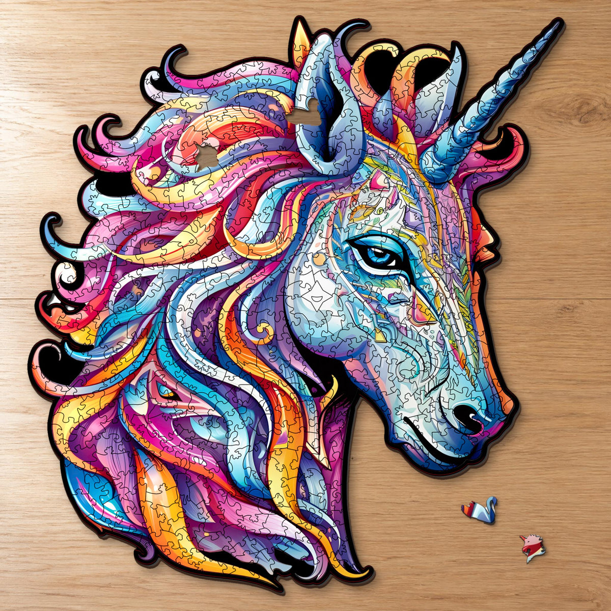 Rainbow Unicorn Wooden Puzzle, almost finished on a light oak table, with the swan and unicorn head pieces in front of it
