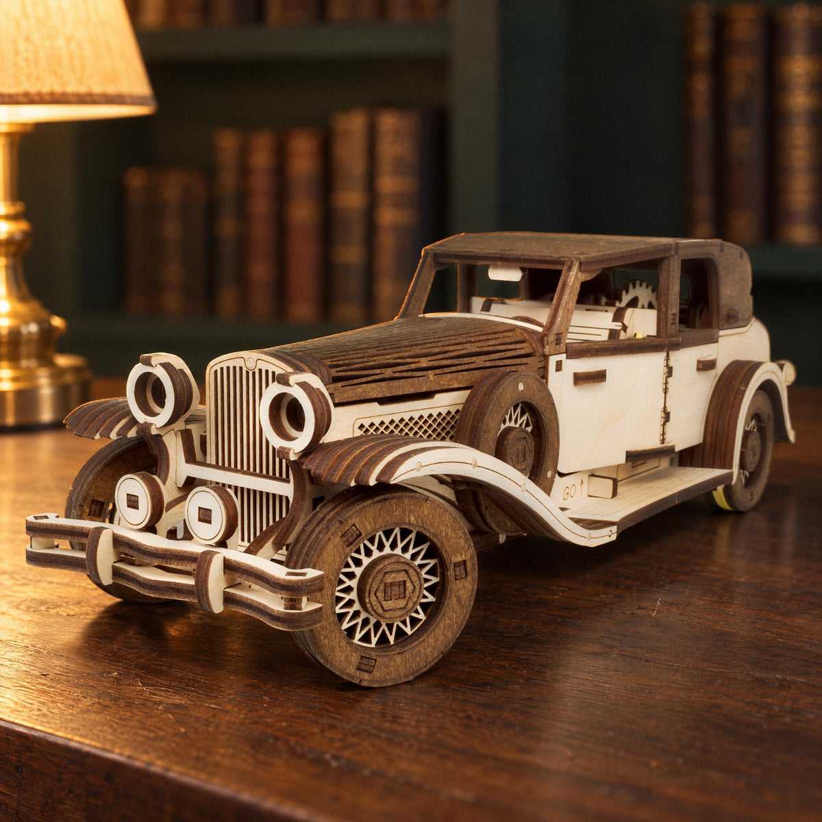 Ferdinand Retro Car, a finished wooden model in the evening light on a dark sideboard against a green wall with a brass lamp