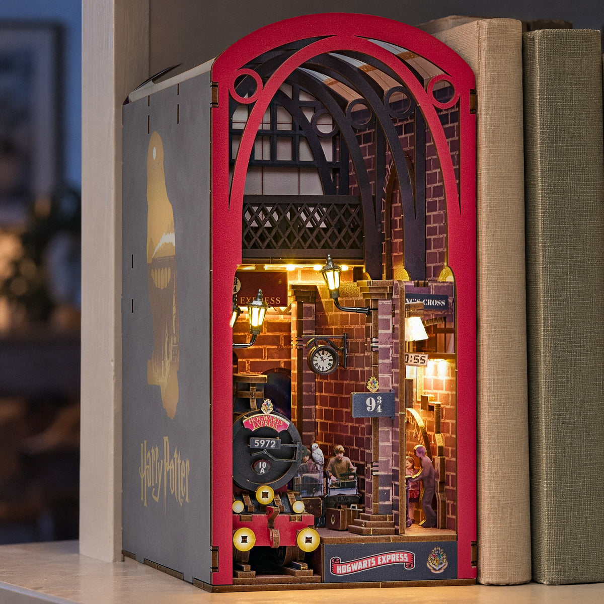 Hogwarts Express Book Nook, een verlichte Harry Potter-diorama van perron 9¾ ’s avonds, naast heldere boeken op de plank