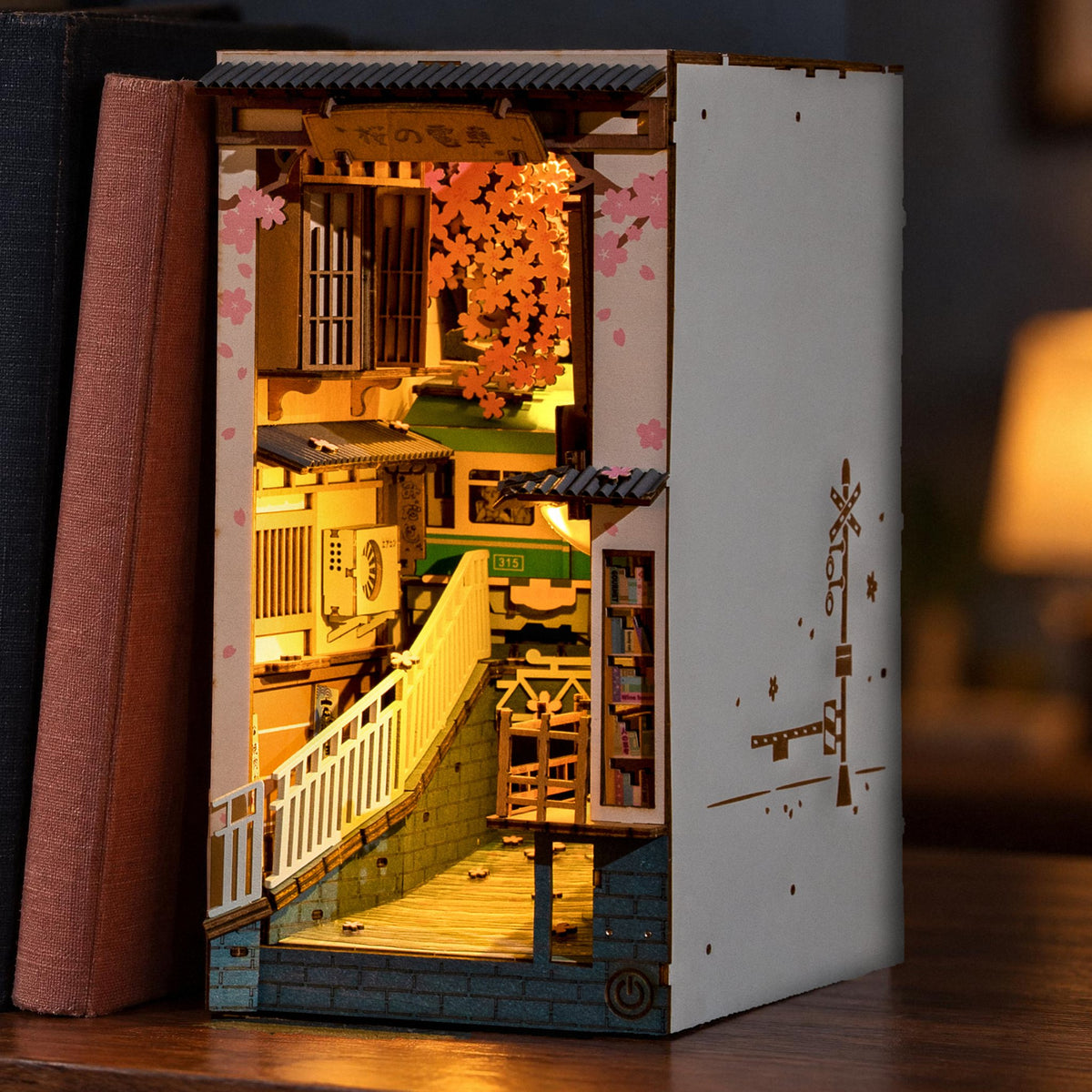 Sakura Densya Book Nook, leuchtende Tokioter Kirschblütenstraße am Ende einer Bücherreihe im Regal am Abend