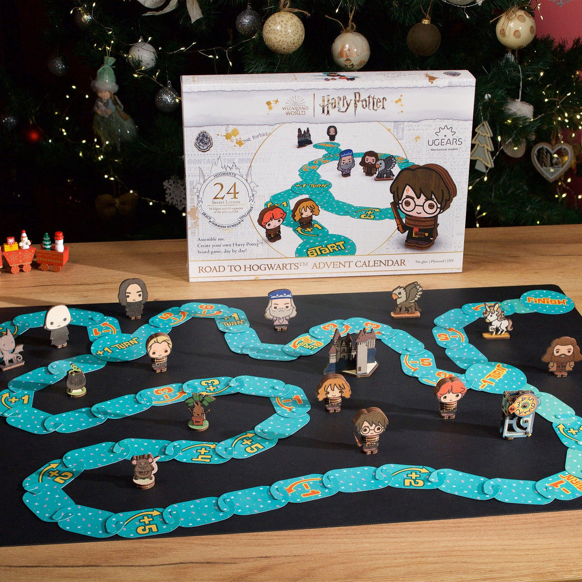Calendrier de l'Avent Harry Potter « Le chemin vers Poudlard » : boîte en carton et jeu de société prêt à l'emploi avec ses figurines, posé devant le sapin de Noël