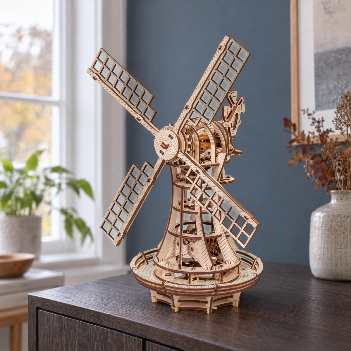 Mechanische Windmühle aus Holz auf einer dunklen Eichenkommode vor blaugrauer Wand, Holzbausatz von Eco-Wood-Art